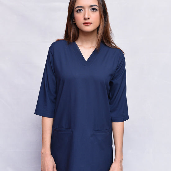 Woman wearing a navy blue top against a plain background