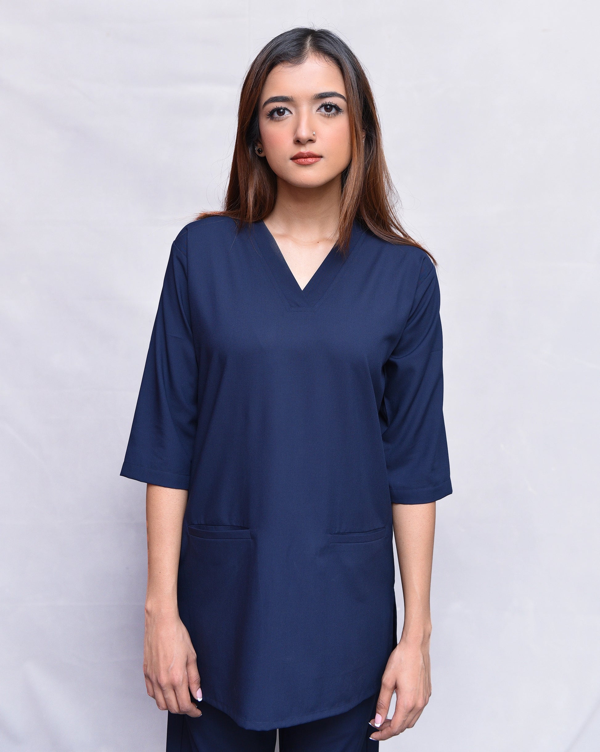 Woman wearing a navy blue top against a plain background