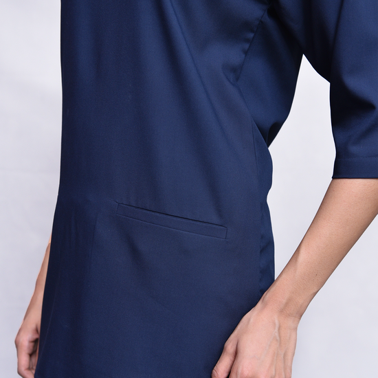 Navy blue scrub top with a pocket, worn by a person.