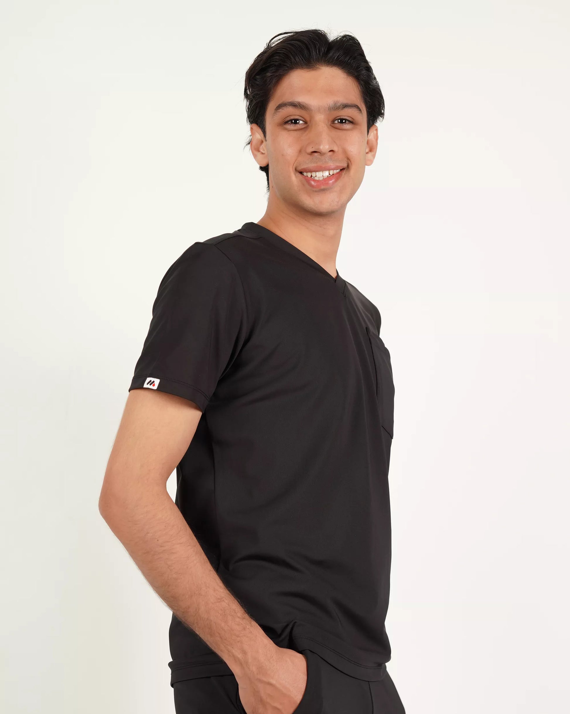 A person wearing a green V-neck scrub shirt with a stethoscope around their neck, featuring multiple pockets.