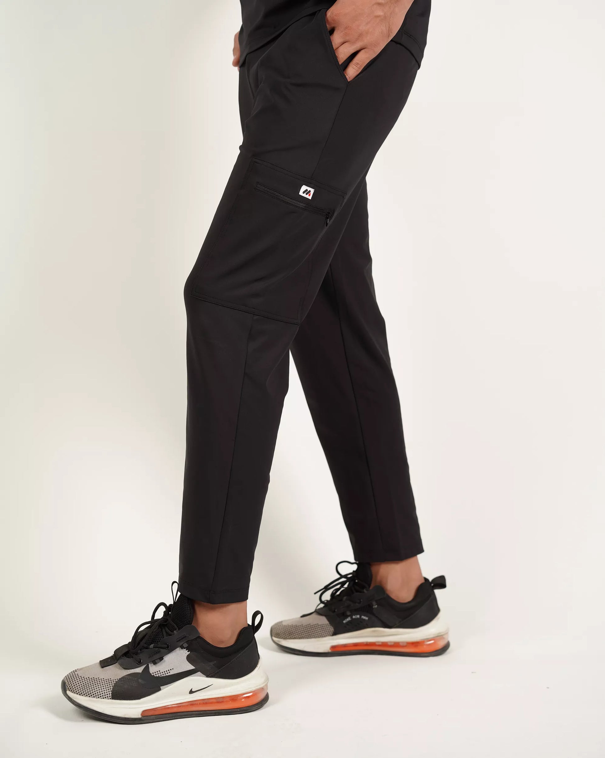 Person wearing black pants and black sneakers on a white background