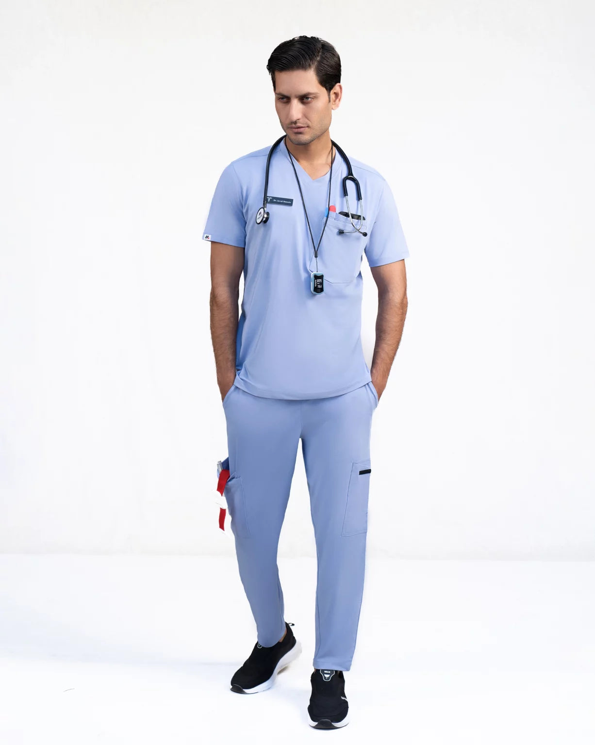 A person wearing a green V-neck scrub shirt with a stethoscope around their neck, featuring multiple pockets.