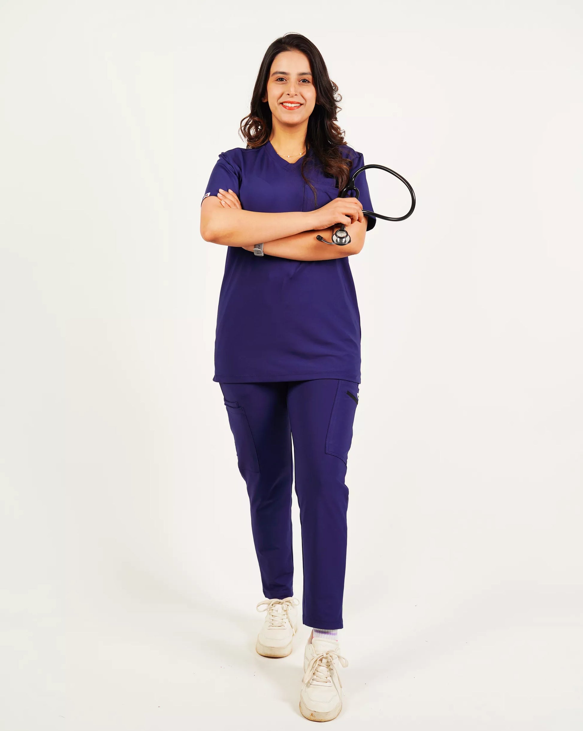 A person wearing a green V-neck scrub shirt with a stethoscope around their neck, featuring multiple pockets.