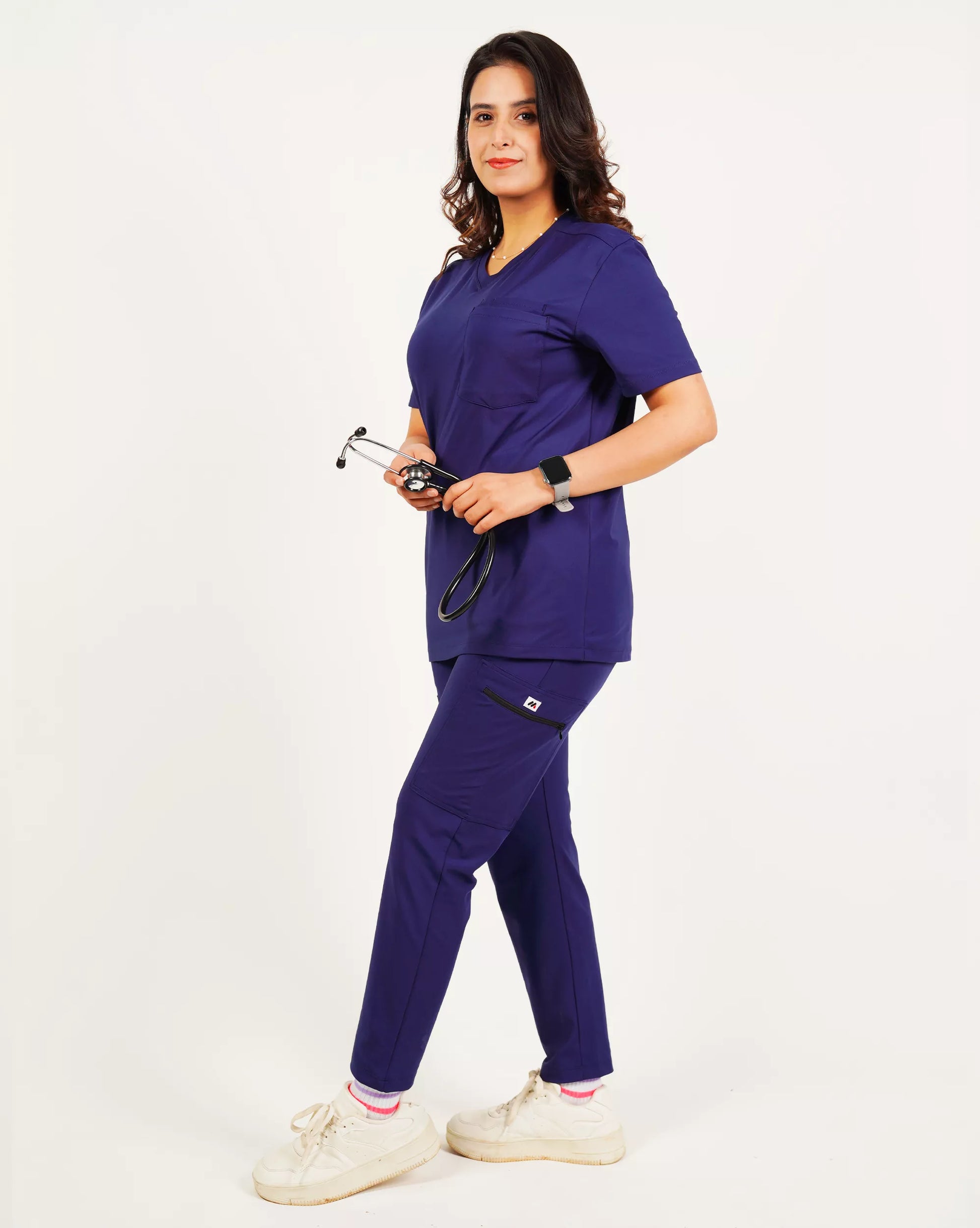 Person wearing purple medical scrubs with a stethoscope on a plain background.