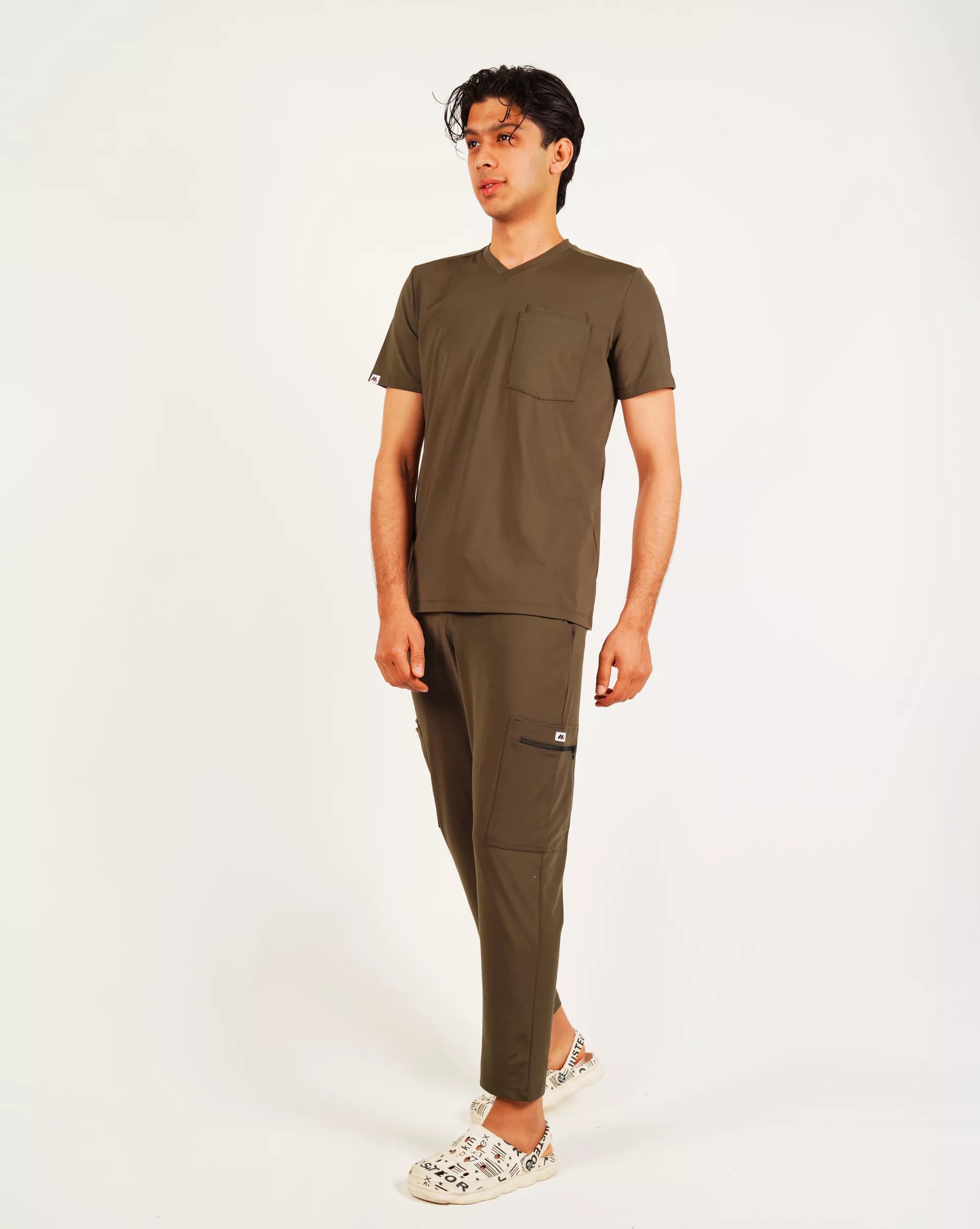 Person wearing a brown scrub set on a white background