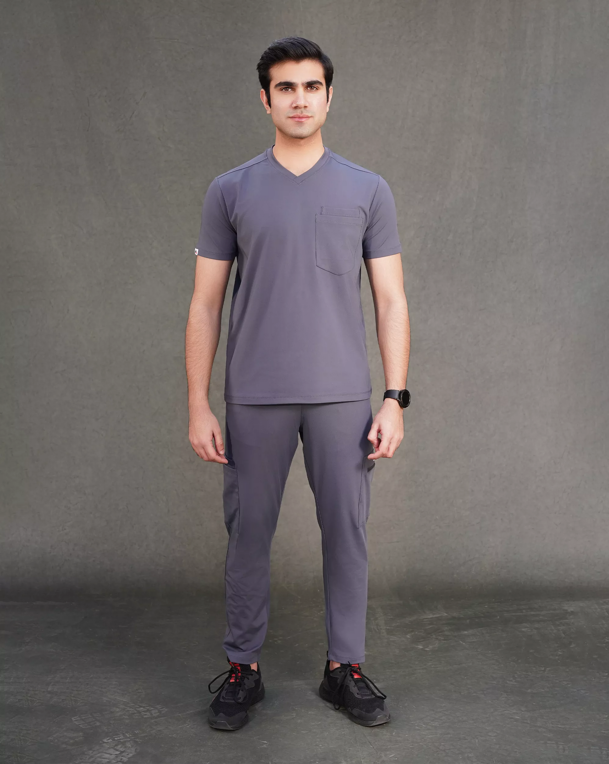 Man wearing a gray t-shirt and pants set on a dark background