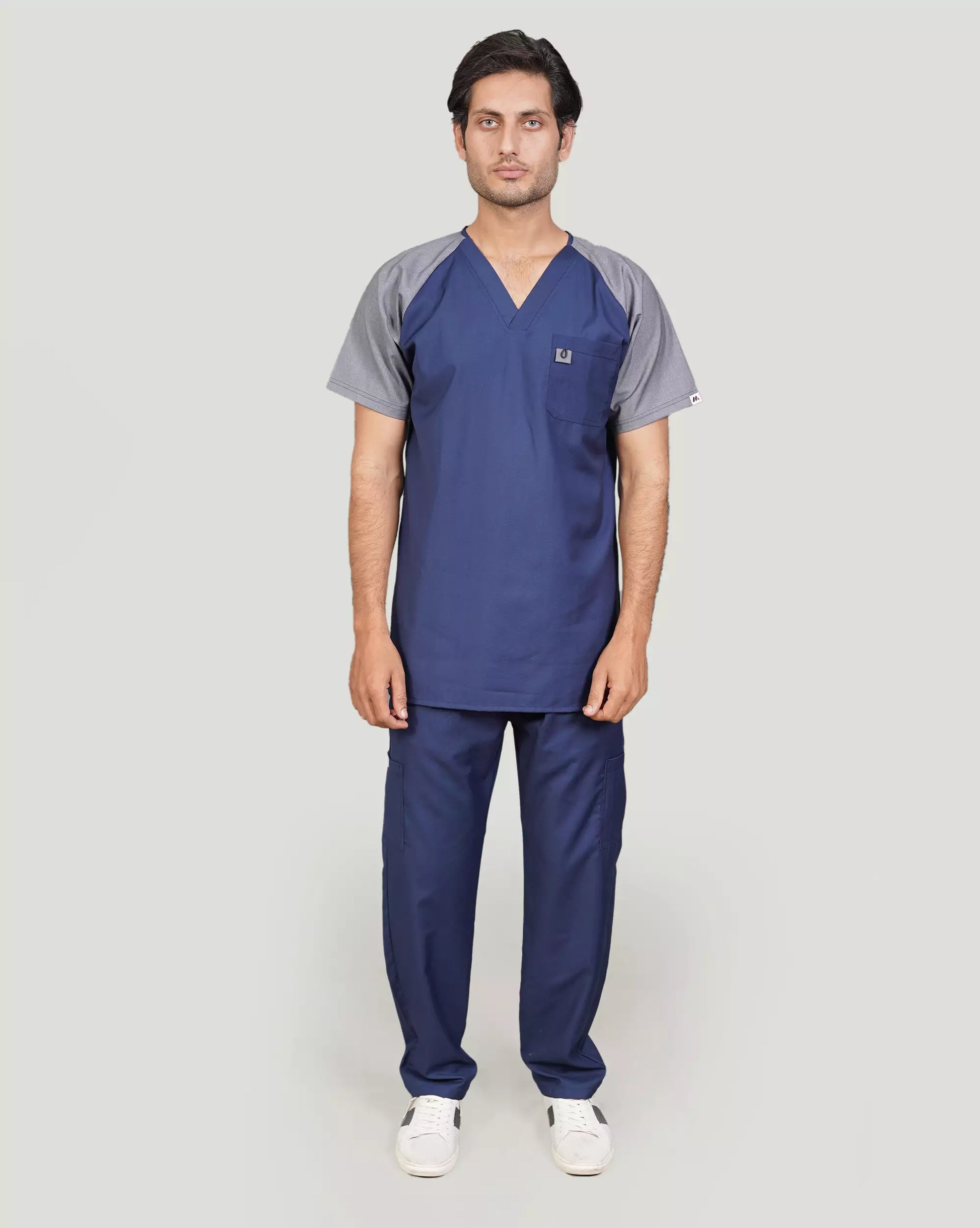 A person wearing a gray and black graphite scrub with a stethoscope, standing with arms crossed.