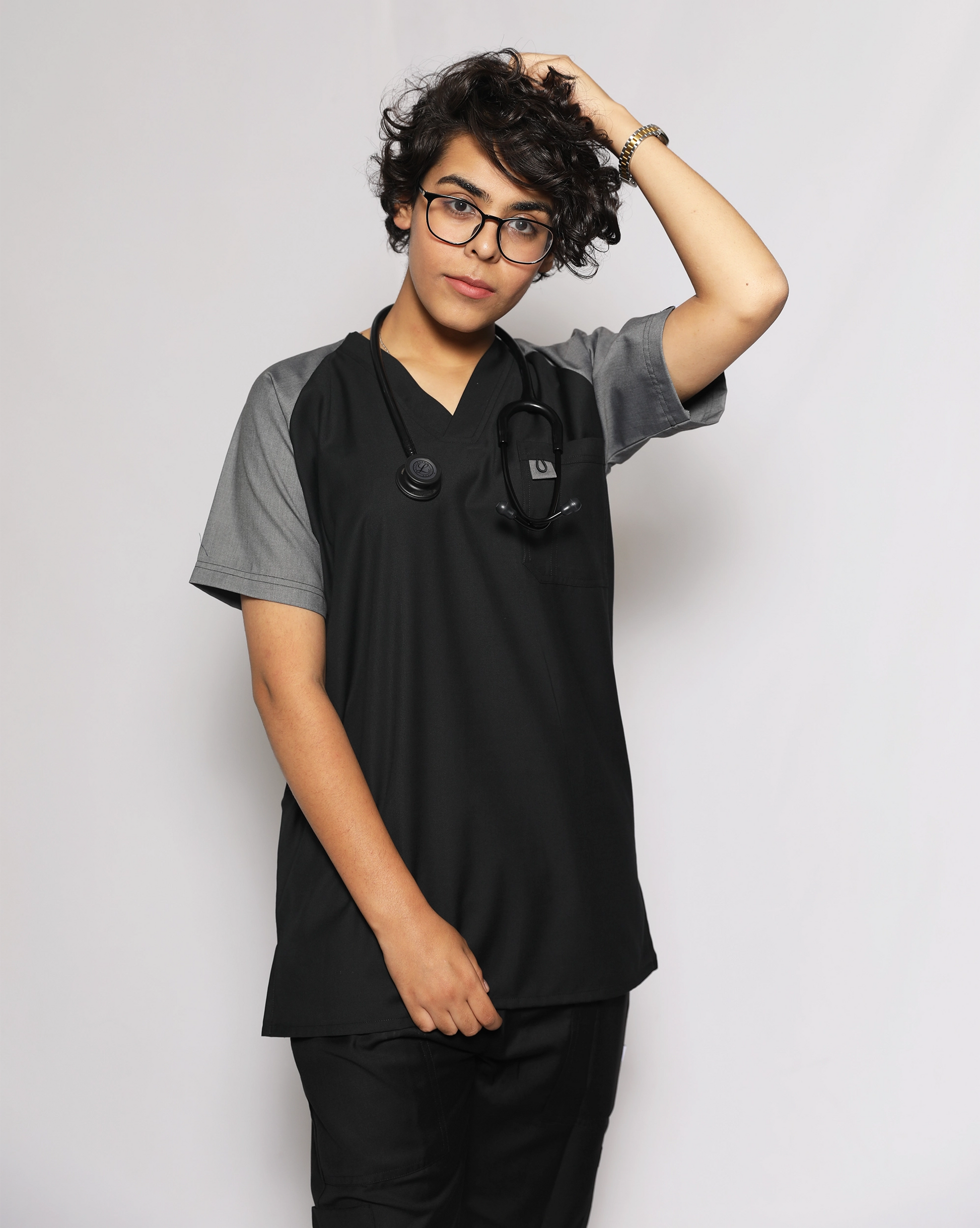 Person wearing black and gray medical scrubs against a plain background.