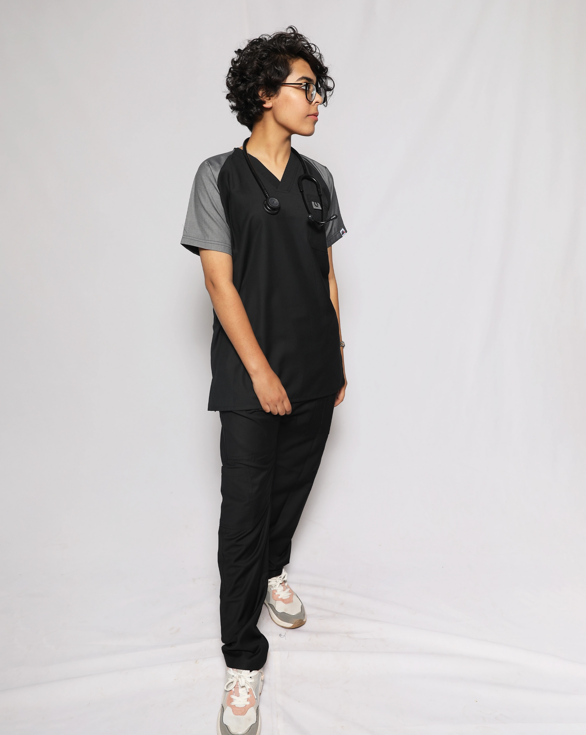 Person wearing black and gray medical scrubs against a white background.