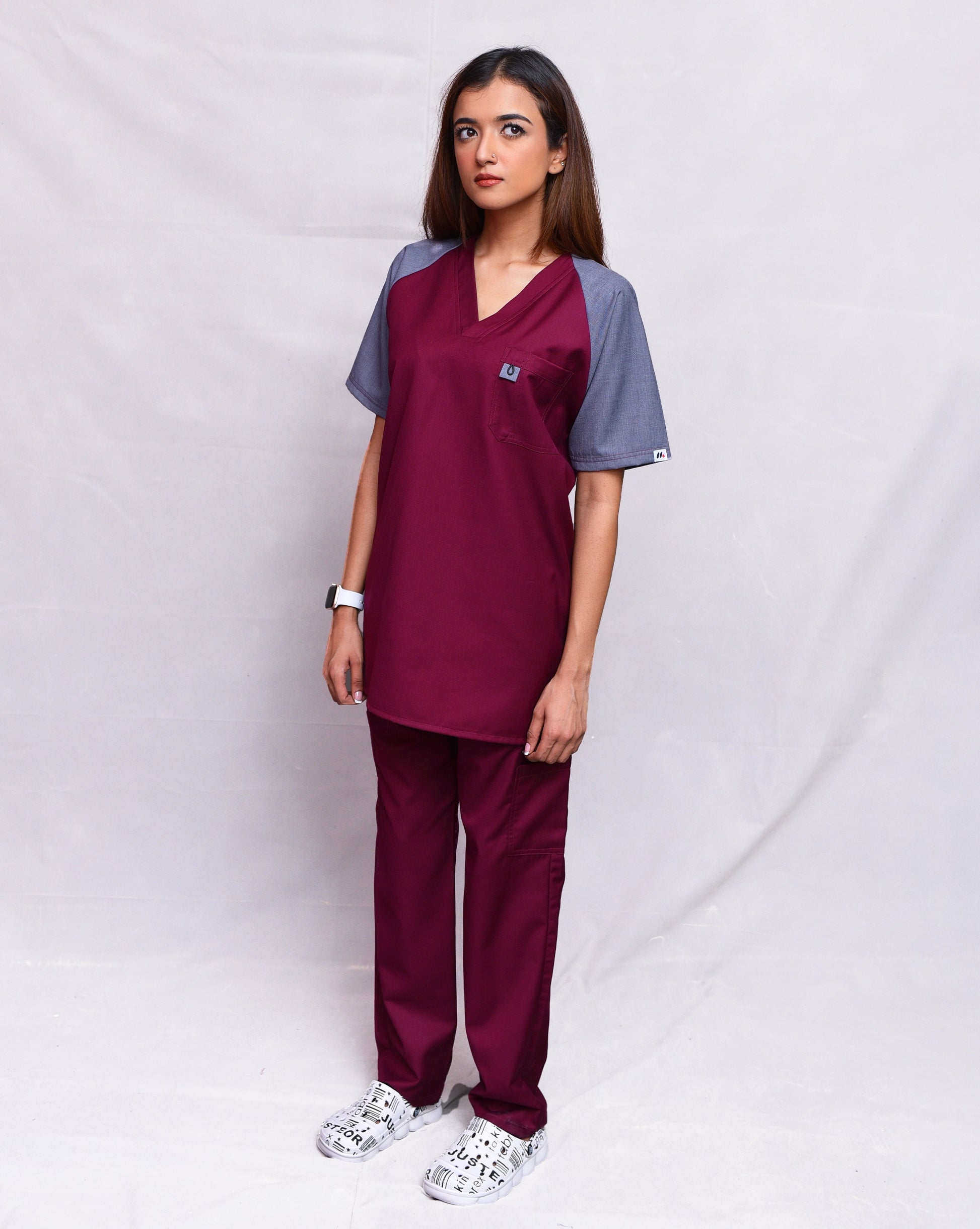 Person wearing a maroon and gray scrub set on a white background
