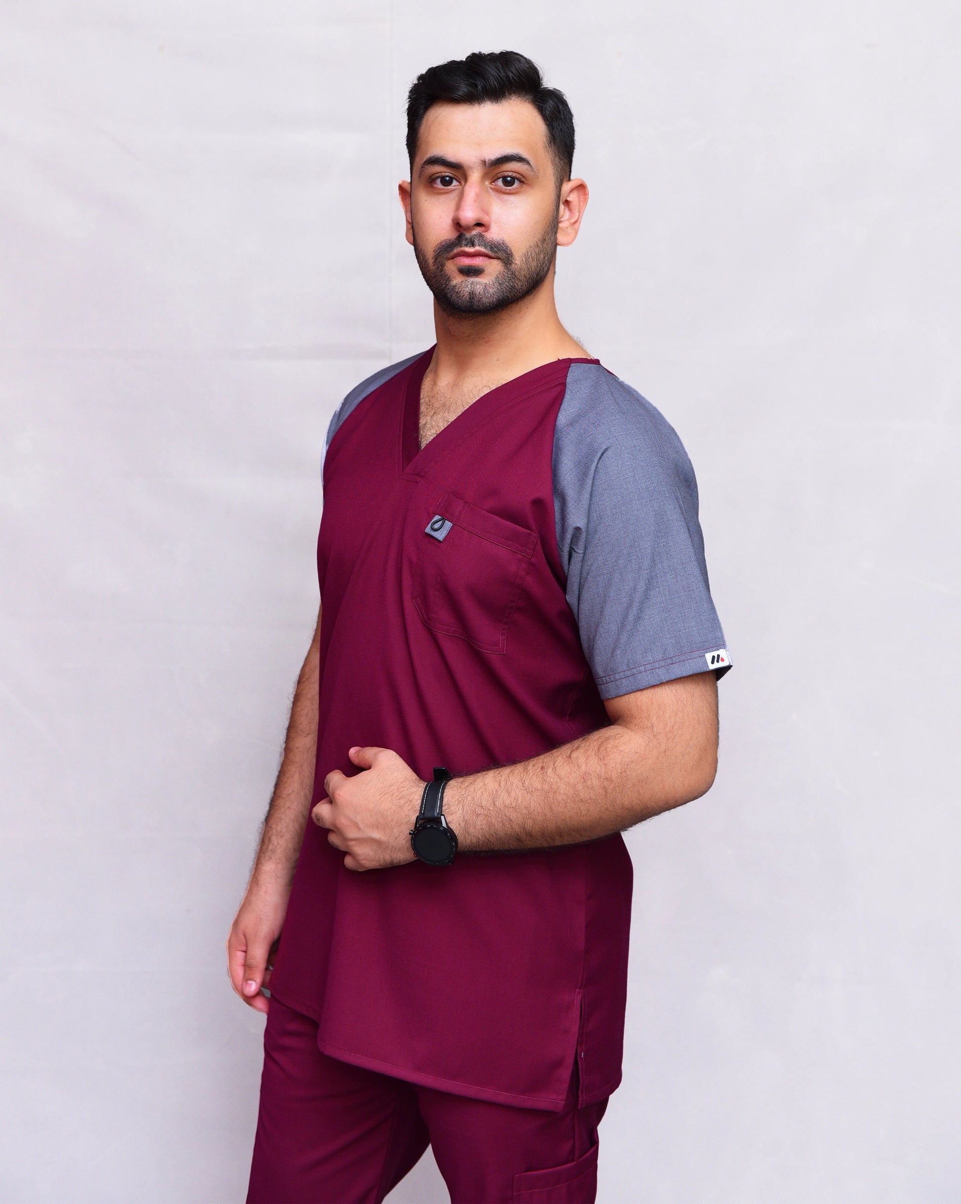 Man wearing maroon and gray scrubs for men top on a plain background