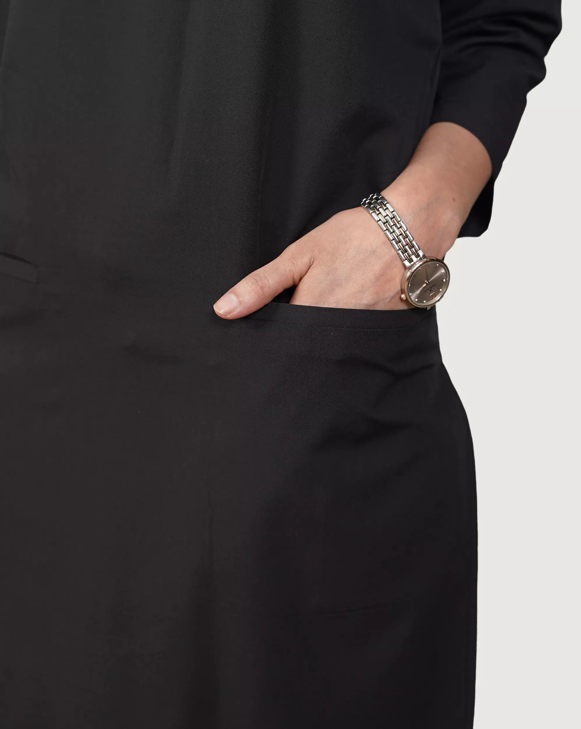 Person wearing a watch and bracelet on a plain background