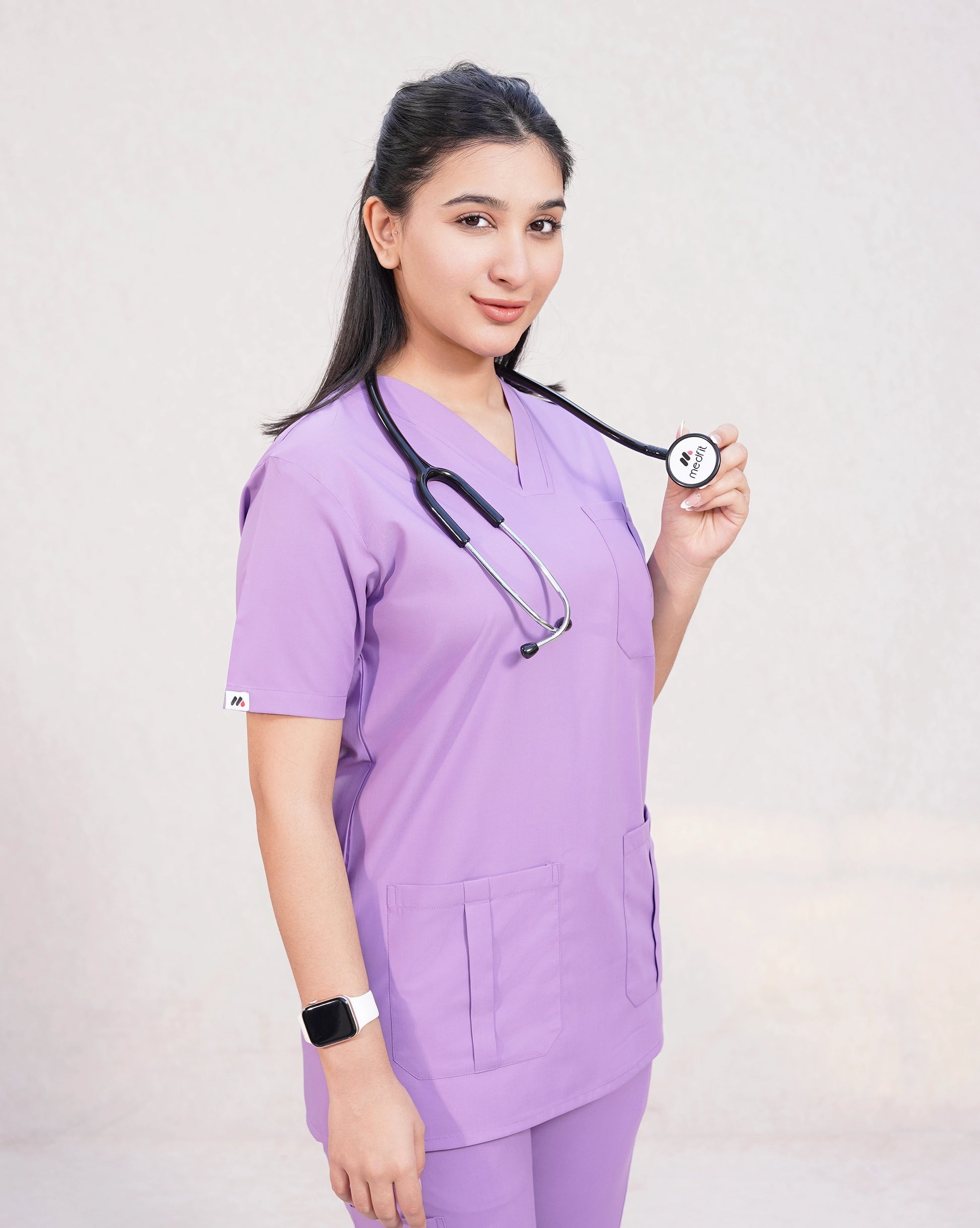 Smiling female medical professional in a lavender Medfit Prime Unisex scrub set with a stethoscope, ideal for modern and comfortable healthcare attire.