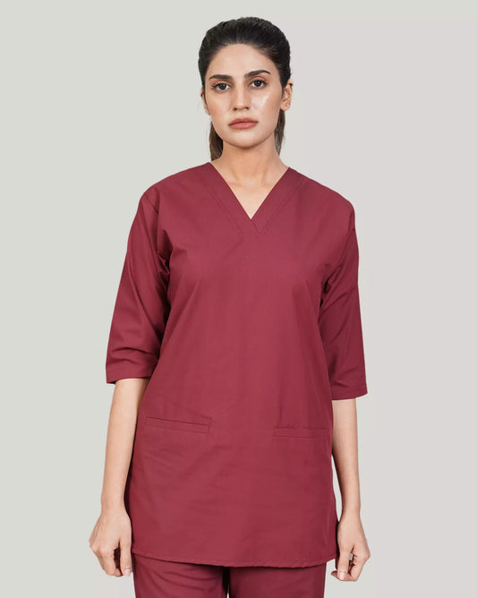 Woman wearing a maroon scrub set against a plain background