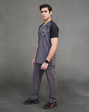 doctor wearing gray medical scrubs with a stethoscope, standing against a gray background.