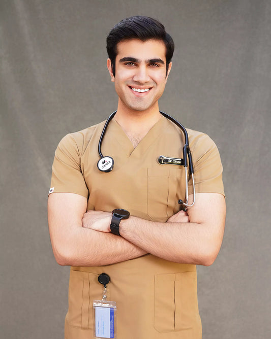 Smiling male doctor confidently posing in a tan 'Earth' colored Medfit men's scrub top with ID badge and stethoscope, ideal for professional medical settings.