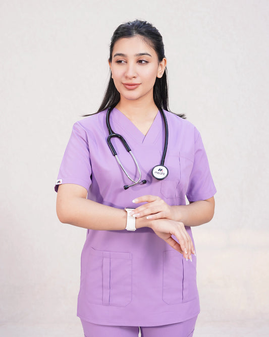 Smiling female medical professional in a lavender Medfit Prime Unisex scrub top, adjusting her smartwatch with a stethoscope, ideal for a functional and stylish uniform.