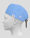 A light blue surgical scrub cap with side buttons for face masks worn on a white mannequin head against a neutral gray background.