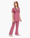 A healthcare professional modeling a matching dusty rose pink medical scrub set from a side angle, wearing a V-neck top and straight-leg pants with a stethoscope.
