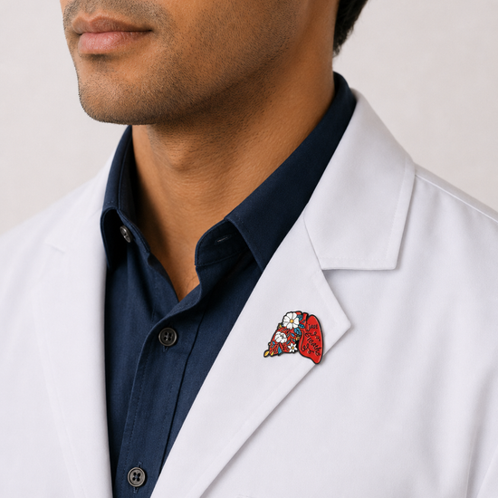 A close-up of a male healthcare professional wearing a white lab coat over a dark blue collared shirt with an anatomical lungs enamel lapel pin against a plain background.