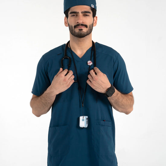 A male model wearing a dark teal blue medical scrub set with a matching surgical cap, stethoscope, and ID badge, MedFit professional medical attire.