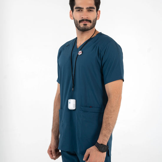 A male model wearing a dark teal blue medical scrub set, featuring a short-sleeve V-neck top with a drawstring and matching scrub pants, MedFit professional healthcare apparel.