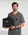 A male model wearing gray medical scrubs and a red stethoscope, holding a black medical supply and organizer bag from MedFit.