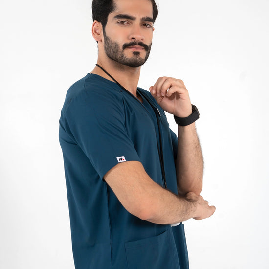Side profile of a male model wearing a short-sleeve dark teal blue V-neck medical scrub top, MedFit professional healthcare apparel.