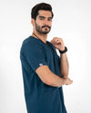 Side profile of a male model wearing a short-sleeve dark teal blue V-neck medical scrub top, MedFit professional healthcare apparel.