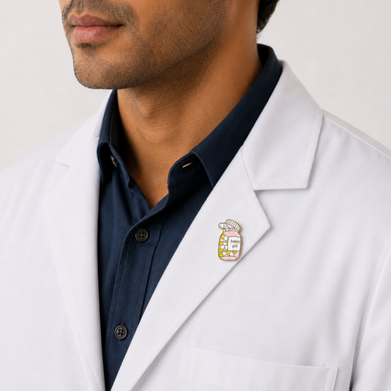 A healthcare professional wearing a crisp white lab coat styled with a unique 'Take Your Meds' pill bottle enamel pin on the lapel.