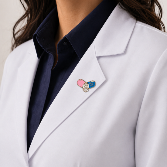 A healthcare professional wearing a crisp white lab coat styled with a unique, colorful pill-shaped enamel pin on the lapel.