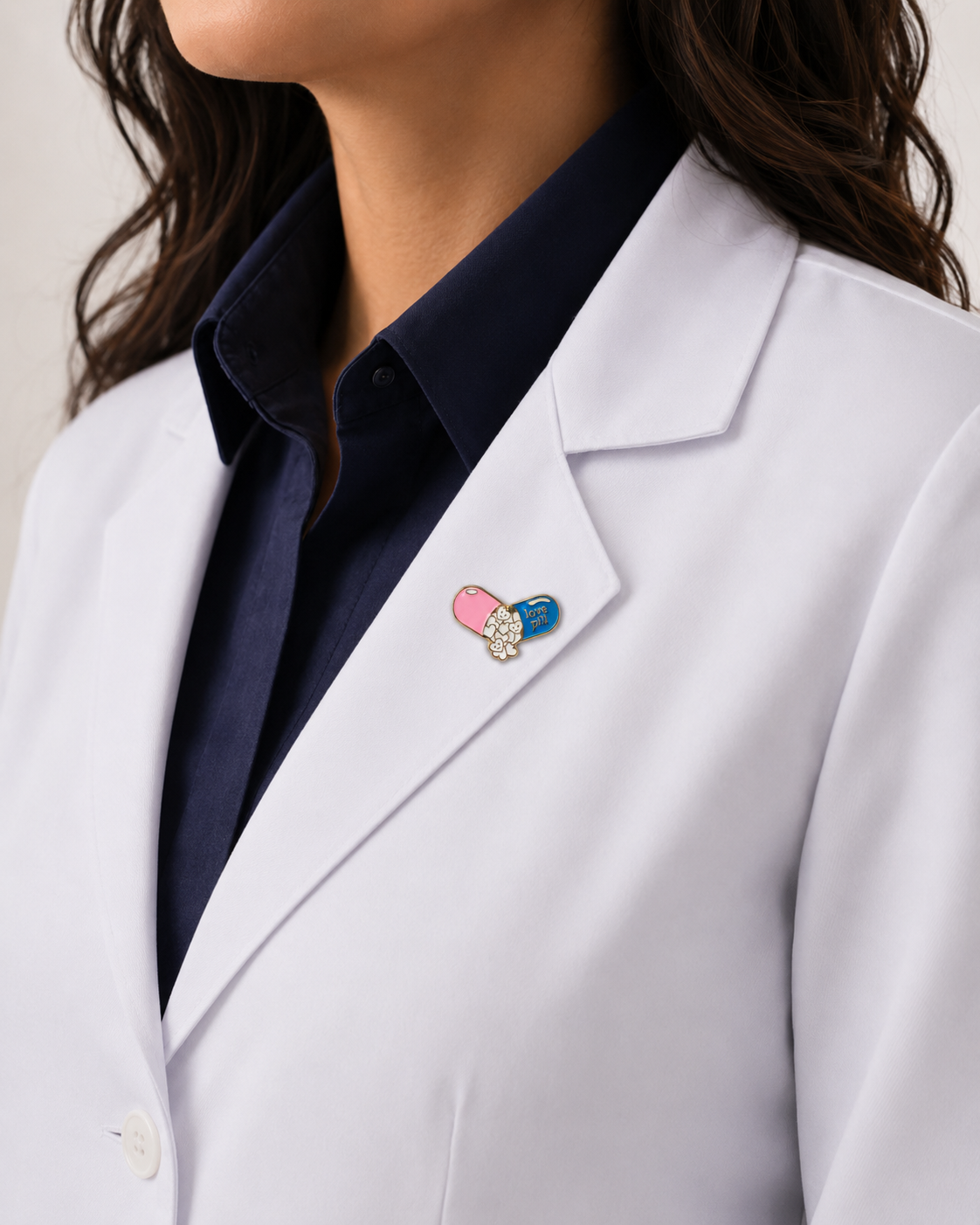 A healthcare professional wearing a crisp white lab coat styled with a unique, colorful pill-shaped enamel pin on the lapel.
