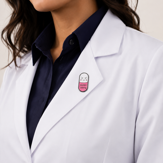 A healthcare professional wearing a crisp white lab coat styled with a cute, pink and white pill-shaped enamel pin on the lapel.