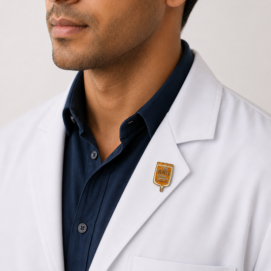 A healthcare professional wearing a crisp white lab coat styled with a gold shield-shaped emblem pin on the lapel.
