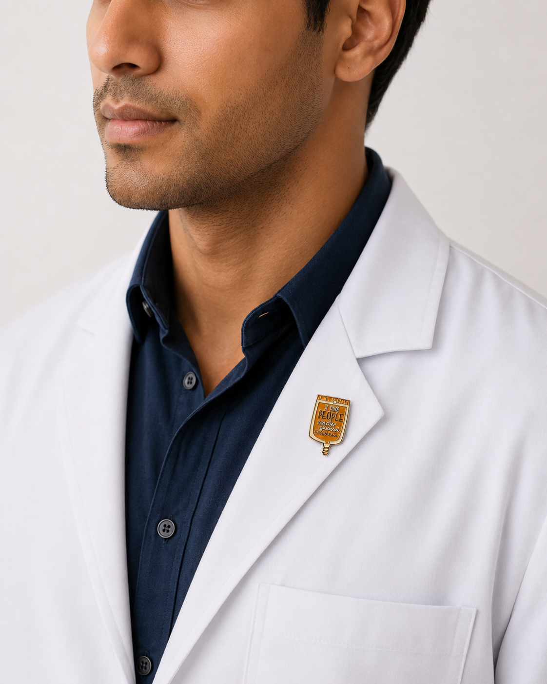 A healthcare professional wearing a crisp white lab coat styled with a gold shield-shaped emblem pin on the lapel.