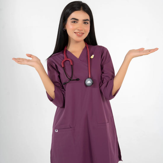 A healthcare professional wearing a purple V-neck medical scrub set with a stethoscope and lapel pin, holding her hands open in a welcoming gesture against a white background.