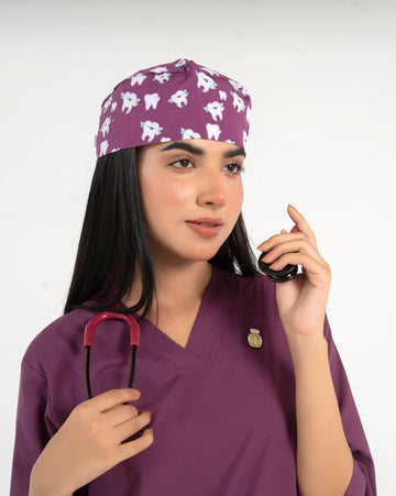 A healthcare professional wearing a purple V-neck medical scrub top, an enamel lapel pin, a matching tooth-pattern scrub cap, and holding a stethoscope against a white background.