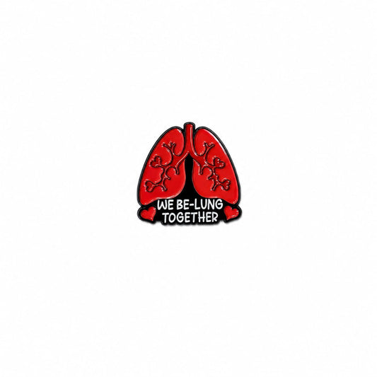 An enamel lapel pin featuring red anatomical lungs with tiny heart details and the text "WE BE-LUNG TOGETHER" against a white background.